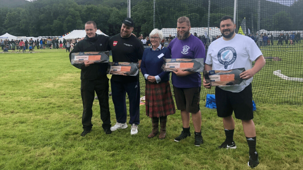 Heavy events athletes and landowner Joanna Macpherson of Attadale Estate at last year's Lochcarron Highland Games, sponsored by the Scottish Salmon Company. Aquaculture is helping maintain the viability of remote communities, a report says. Photo: SSC.