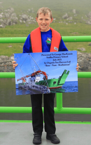 George MacKenzie, 8, with the commemorative poster presented on board the Bàta nam Bràthairean by OSH co-founder Alister MacKinnon. Click on image to enlarge. Photo: OSH. George MacKenzie, 8, with the commemorative poster presented on board the Bàta nam Bràthairean by OSH co-founder Alister MacKinnon. Click on image to enlarge. Photo: OSH.