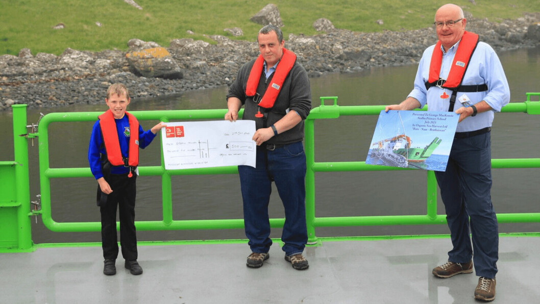 Staffin Primary School pupil George MacKenzie receives a £500 cheque for his school from OSH chief operating oficer Robert Wyvill. OSH co-founder Alister MacKinnon, right, presentedGeorge with a commemorative poster. Photo: OSH.
